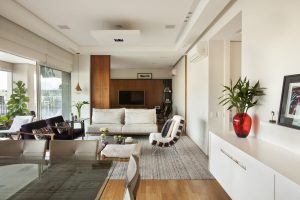 Sala ampla com living, jantar e home theater integrados e separados por painel de madeira deslizante.