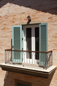 Sacada do quarto com gradil de ferro e Pinho de Riga, desenhados pela arquiteta. Caixilharia pintadas de branco com venezianas verde.