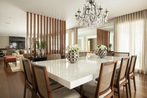 Sala de jantar com mesa em marmoglass e espelho bisotado, separada do living por biombo de madeira.
