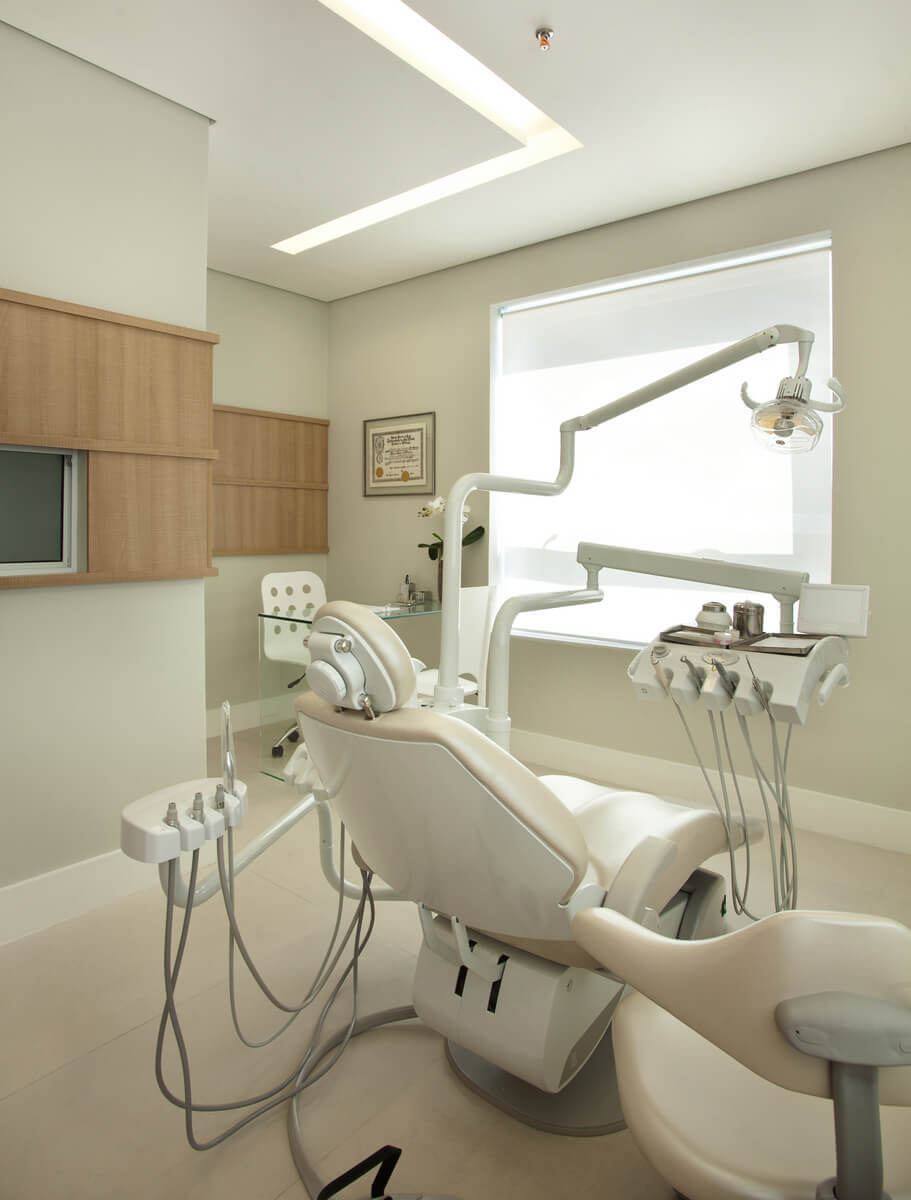 Sala de consulta com cadeira de dentista e mesinha para atendimento.