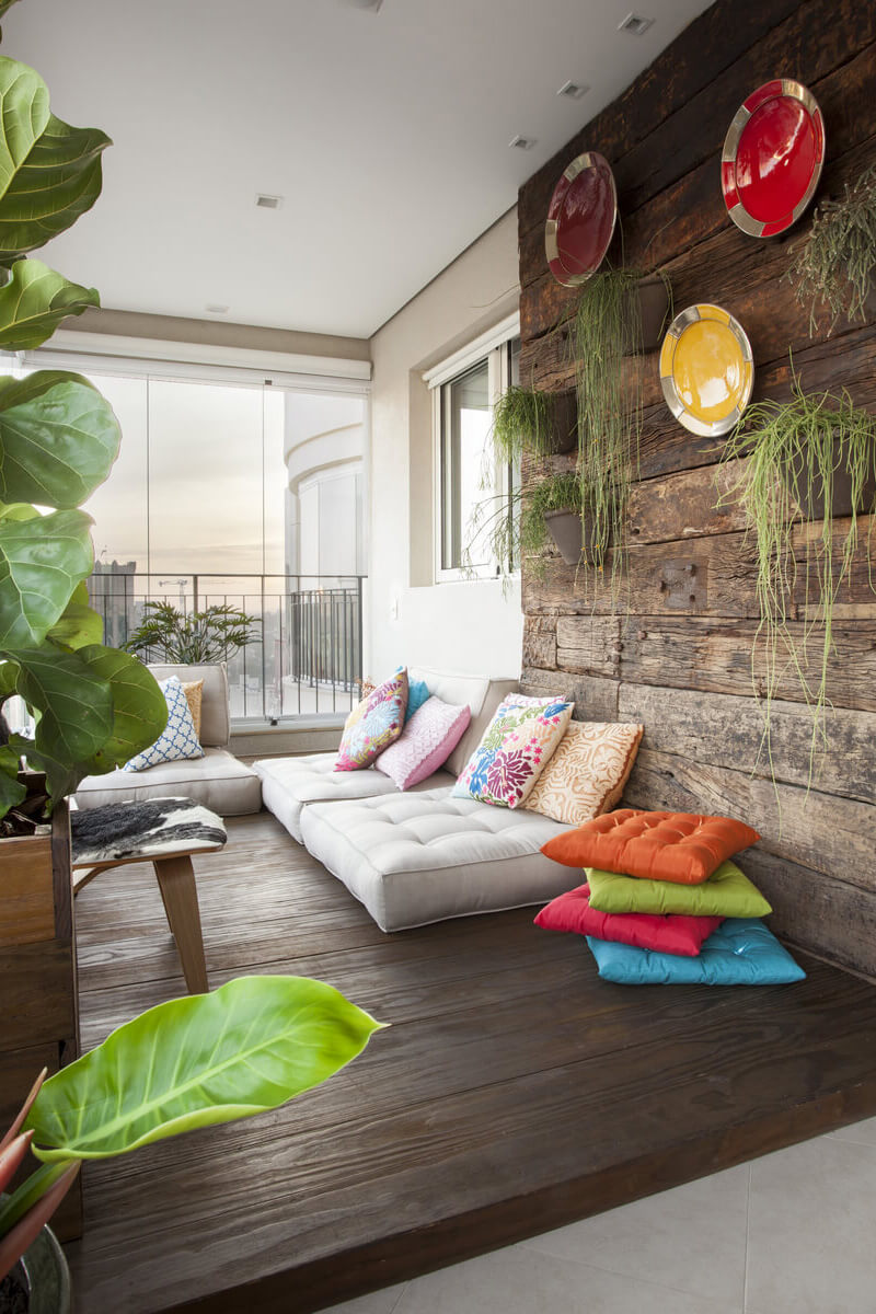 Painel de madeira de demolição com arranjos de pratos e vasos de plantas. Deck de madeira com futons, o canto preferido dos adolescentes.