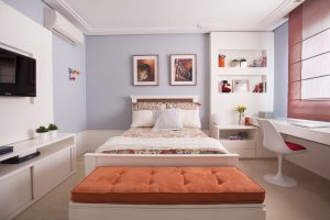 Quarto feminino em tons de laranja com nichos, bancada e cama em laca branca. Cortina romana.