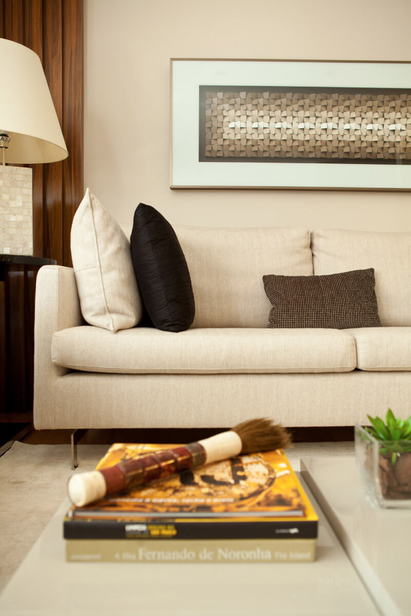 No detalhe do living, destaque para tela sobre o sofá e para a mesa de centro de vários níveis da Artefacto.