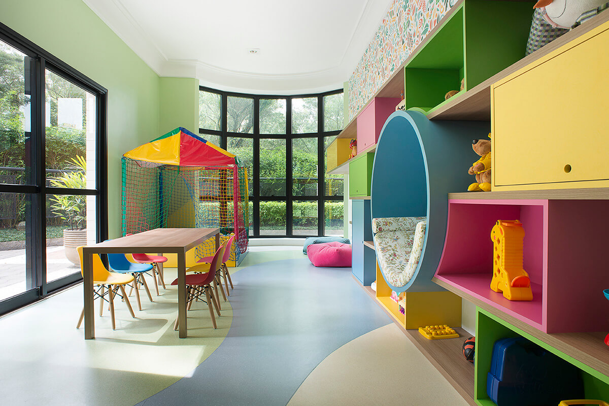 brinquedoteca colorida com nichos abertos e fechados, espaço para leitura, estante para livros, piso vinílico com desenho orgânico
