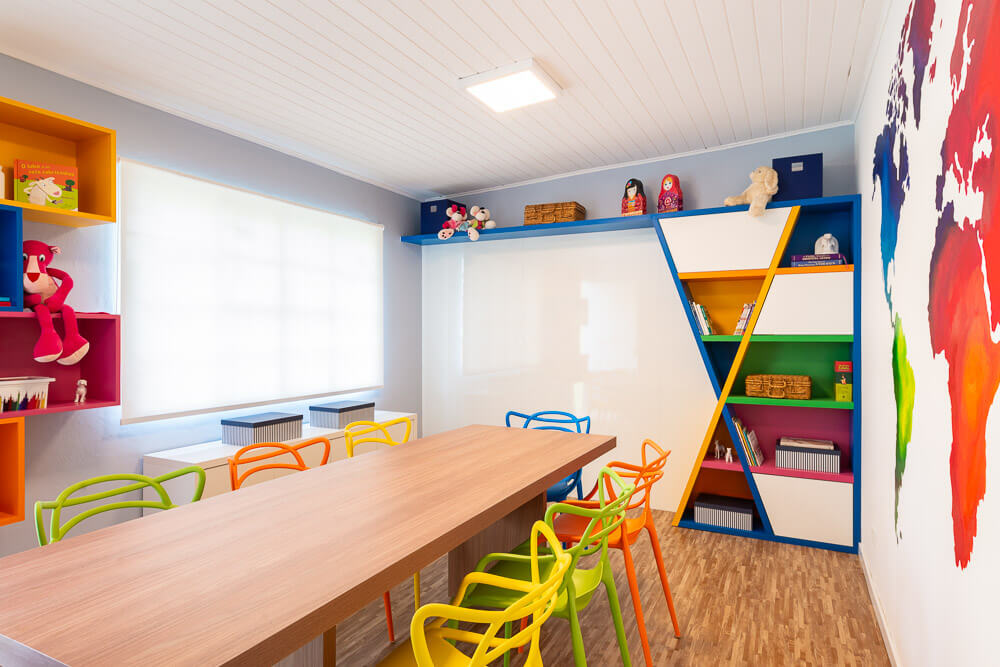 sala de estudos com marcenaria em nichos coloridos e mapa mundi na parede