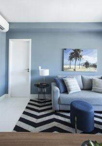sala com parede azul, tapete geometrico e quadro do Rio de Janeiro