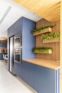 Detalhe de jardineiras na cozinha sobre painel de madeira na marcenaria azul